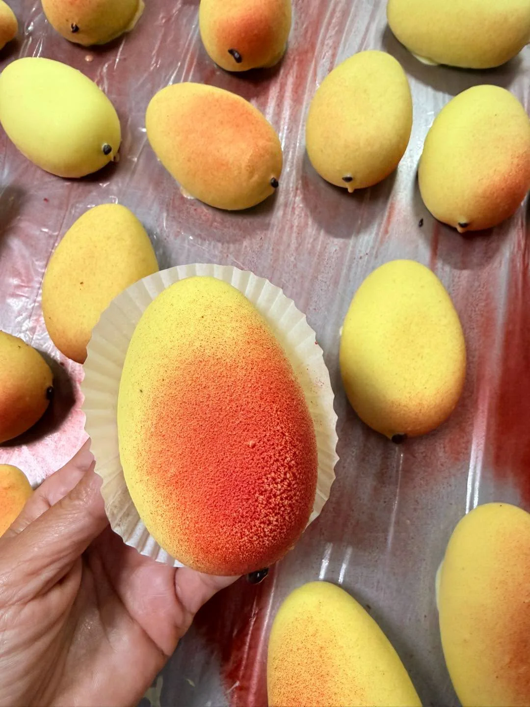 Prăjitură în formă de mango, ținută în mână
